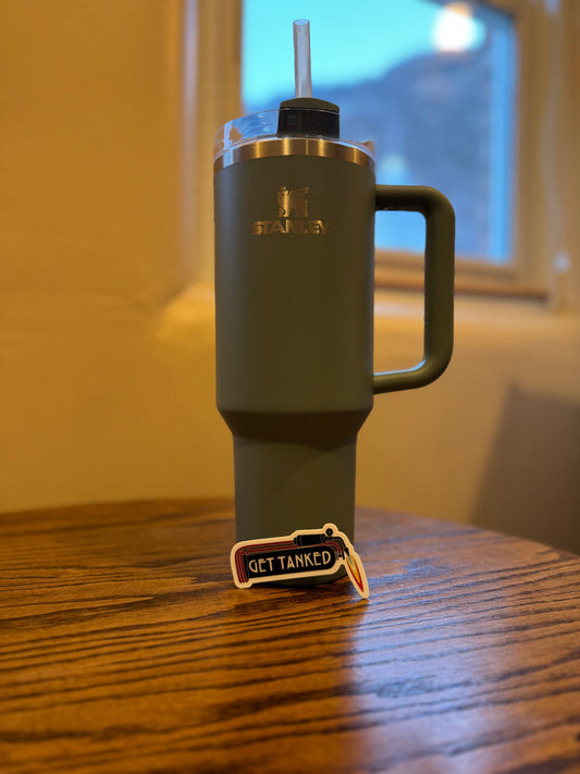 A sticker with the text 'GET TANKED' placed on a wooden surface, with a grey water bottle in the background.