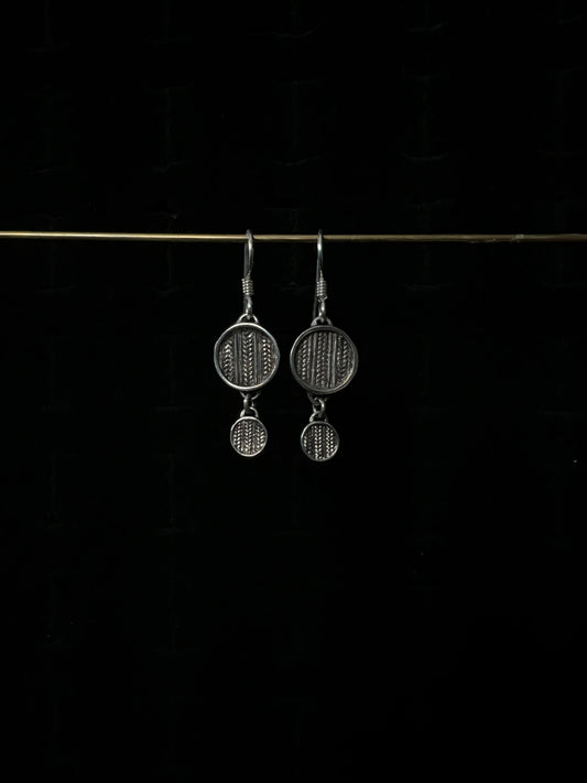 A pair of silver tiered sweater drop earrings displayed against a dark background.
