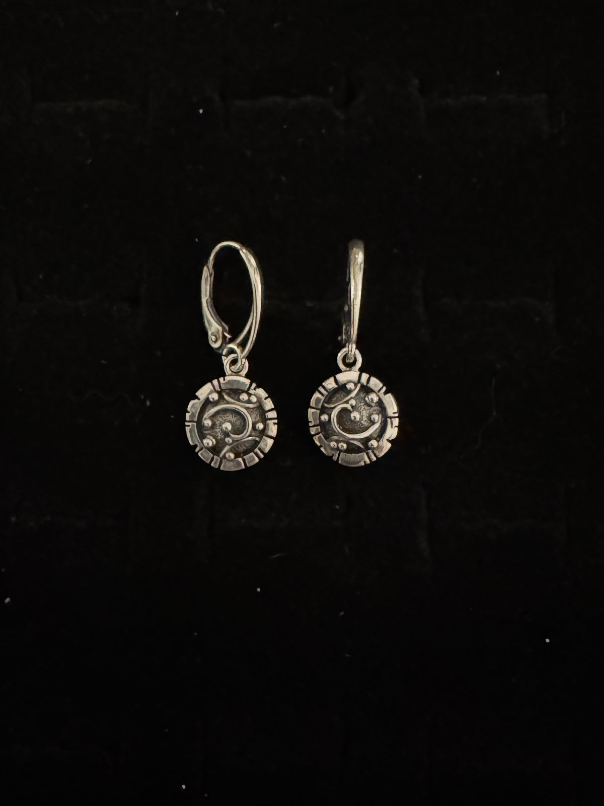Pair of silver earrings on a black background
