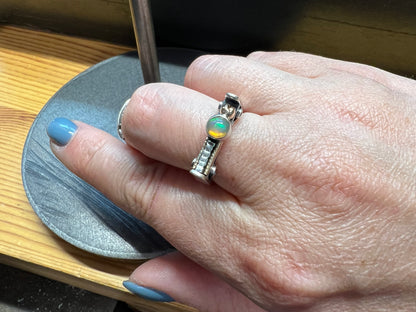 Sterling Silver Bar Ring with Opal and Yellow Gold Accents – lifestyle shot of handcrafted sterling silver bar ring with white opal and yellow gold accents worn on finger, black background