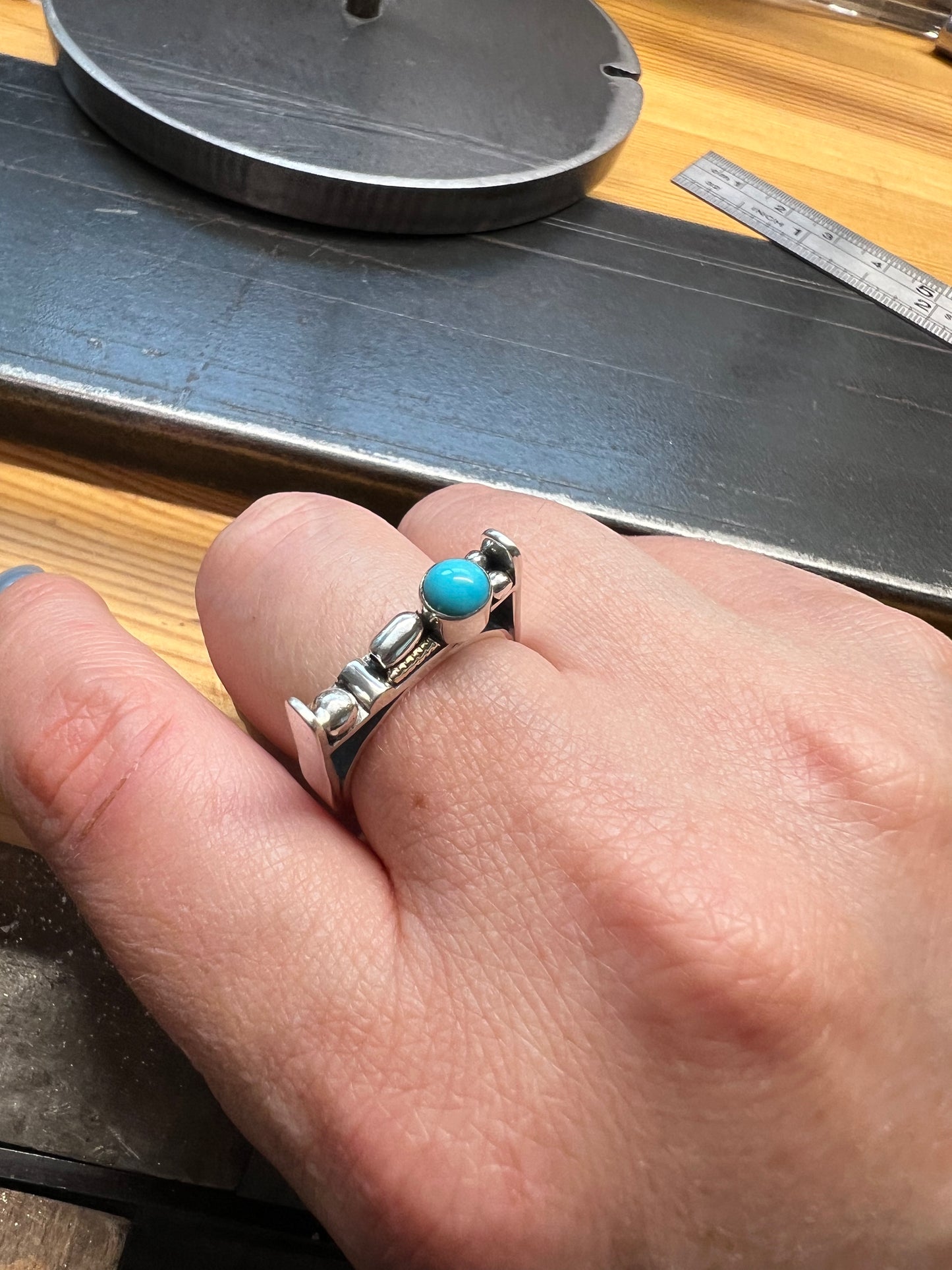 Sterling Silver Bar Ring with Turquoise and Rose Gold Accents – lifestyle shot of handcrafted sterling silver bar ring with turquoise and rose gold accents worn on finger, black background