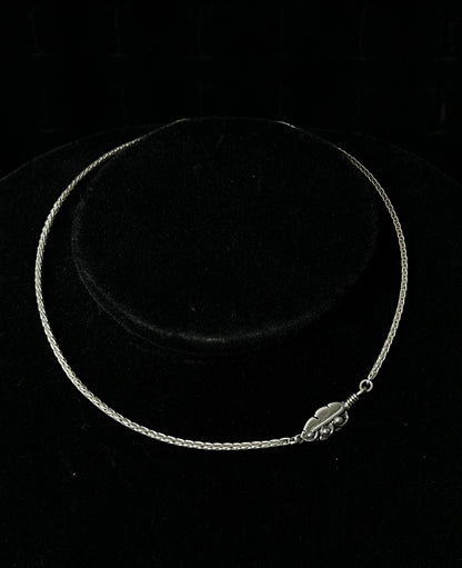 A sterling silver necklace with an embedded feather-shaped pendant, displayed against a black background.