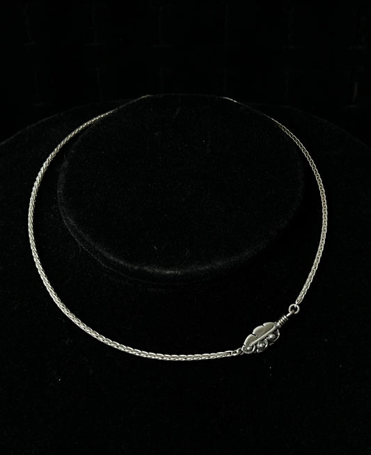A sterling silver necklace with an embedded feather-shaped pendant, displayed against a black background.
