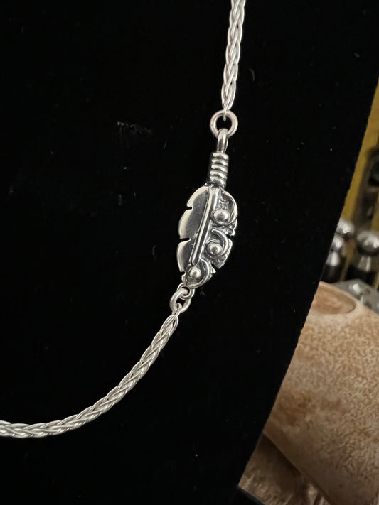 Embedded Feather Necklace – close-up of sterling silver bezel-set resin pendant with embedded natural feather on box chain, black background