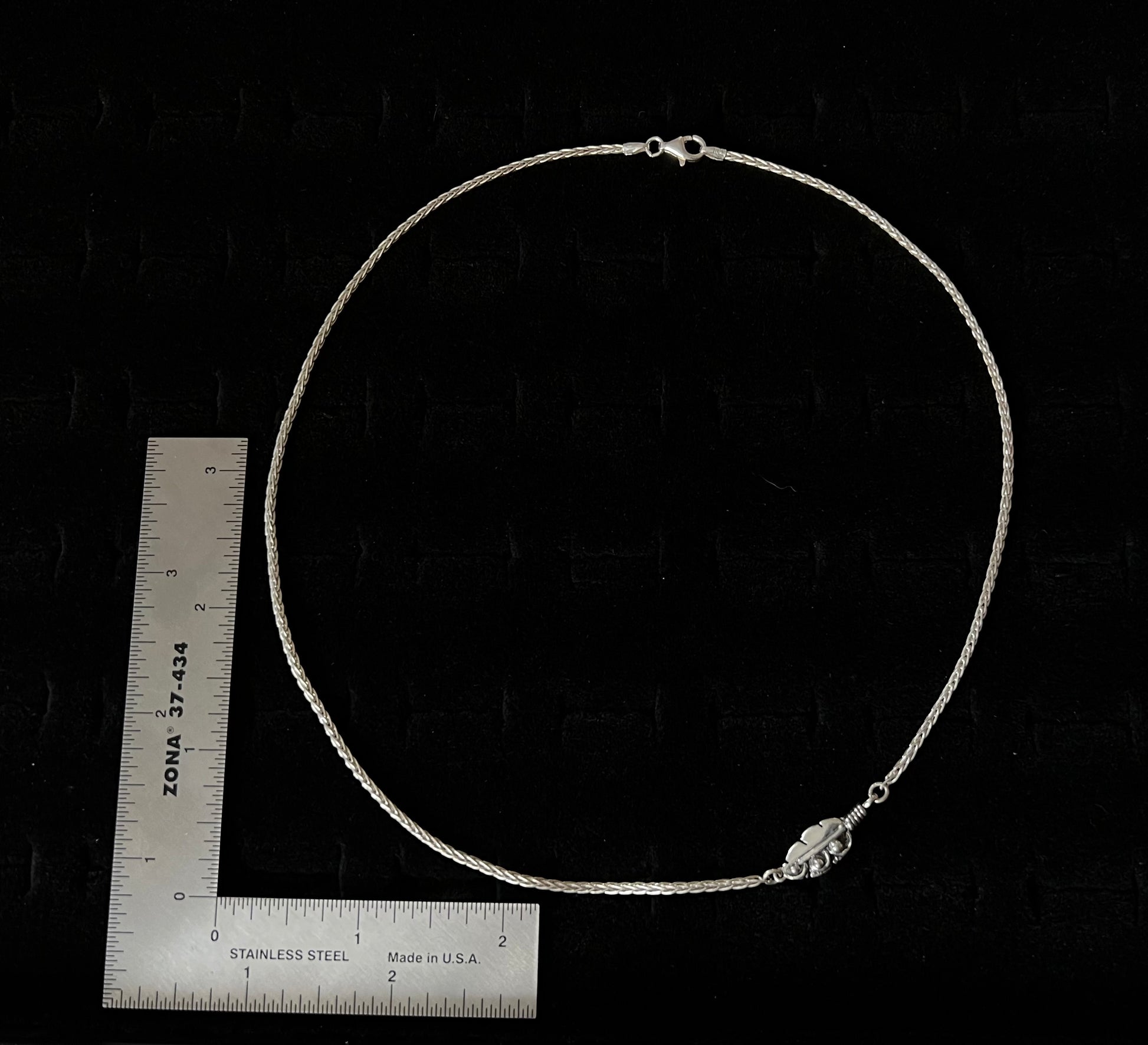 Embedded Feather Necklace – size reference showing sterling silver embedded feather resin pendant approximately 1 inch wide next to ruler, black background