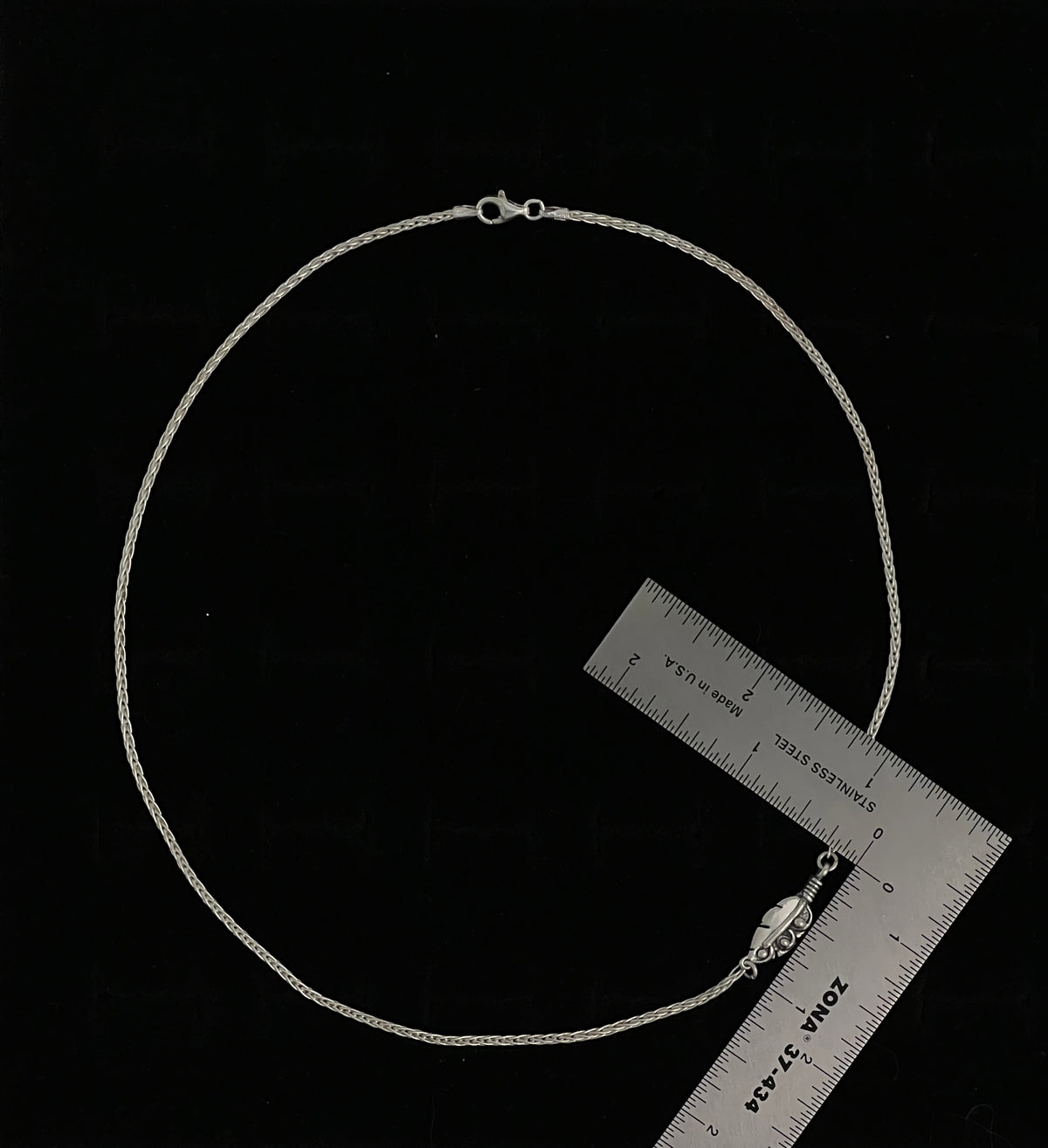 Embedded Feather Necklace – side view of sterling silver bezel-set resin pendant with natural feather detail on box chain, black background