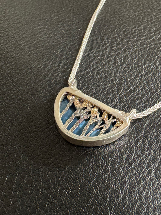 Silver necklace with a half-circle pendant on a dark textured surface