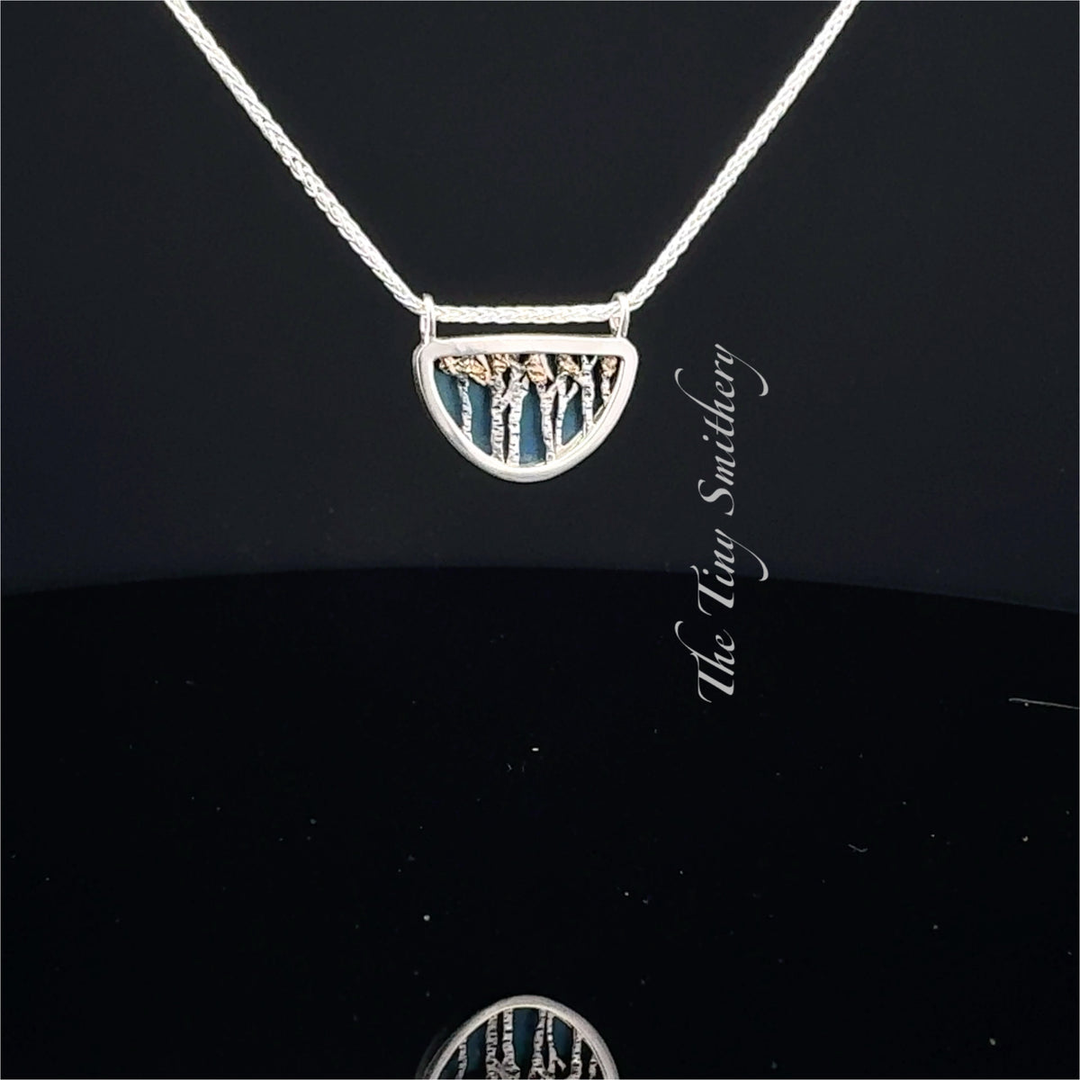 Silver necklace with a tree pendant on a black background