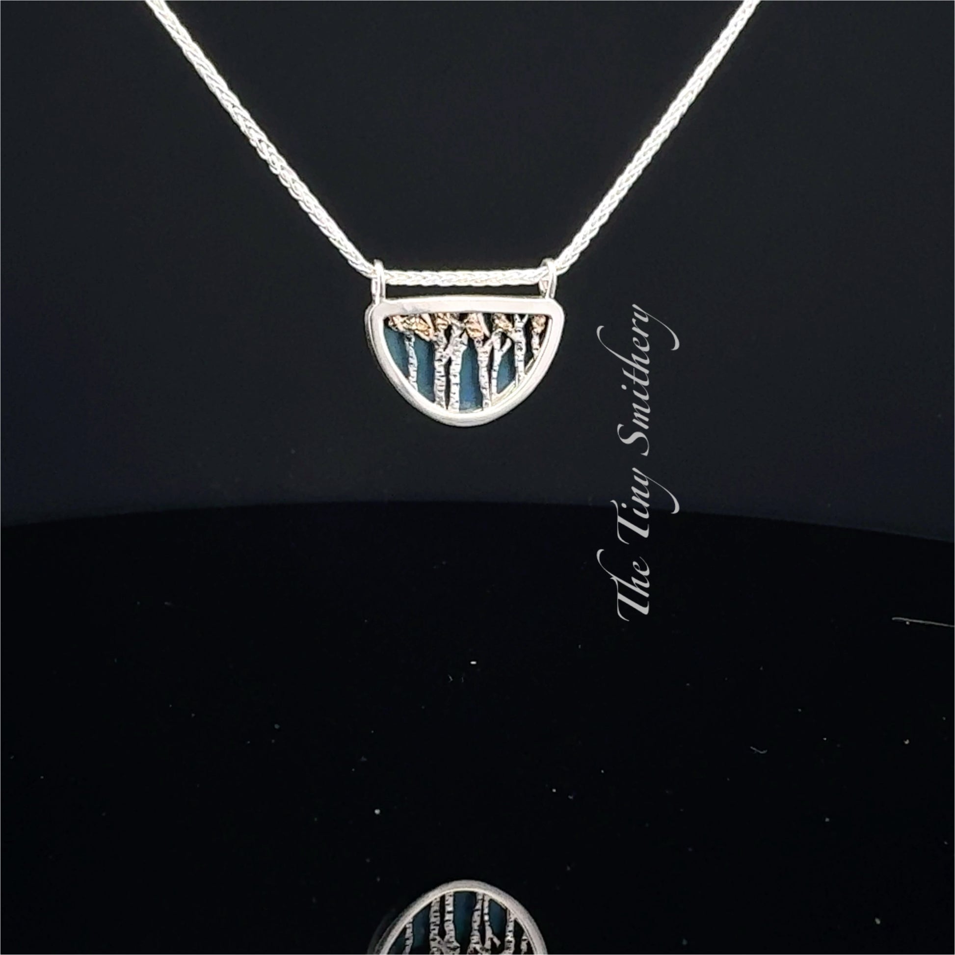 Silver necklace with a tree pendant on a black background