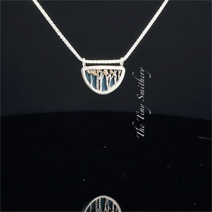 Silver necklace with a tree pendant on a black background
