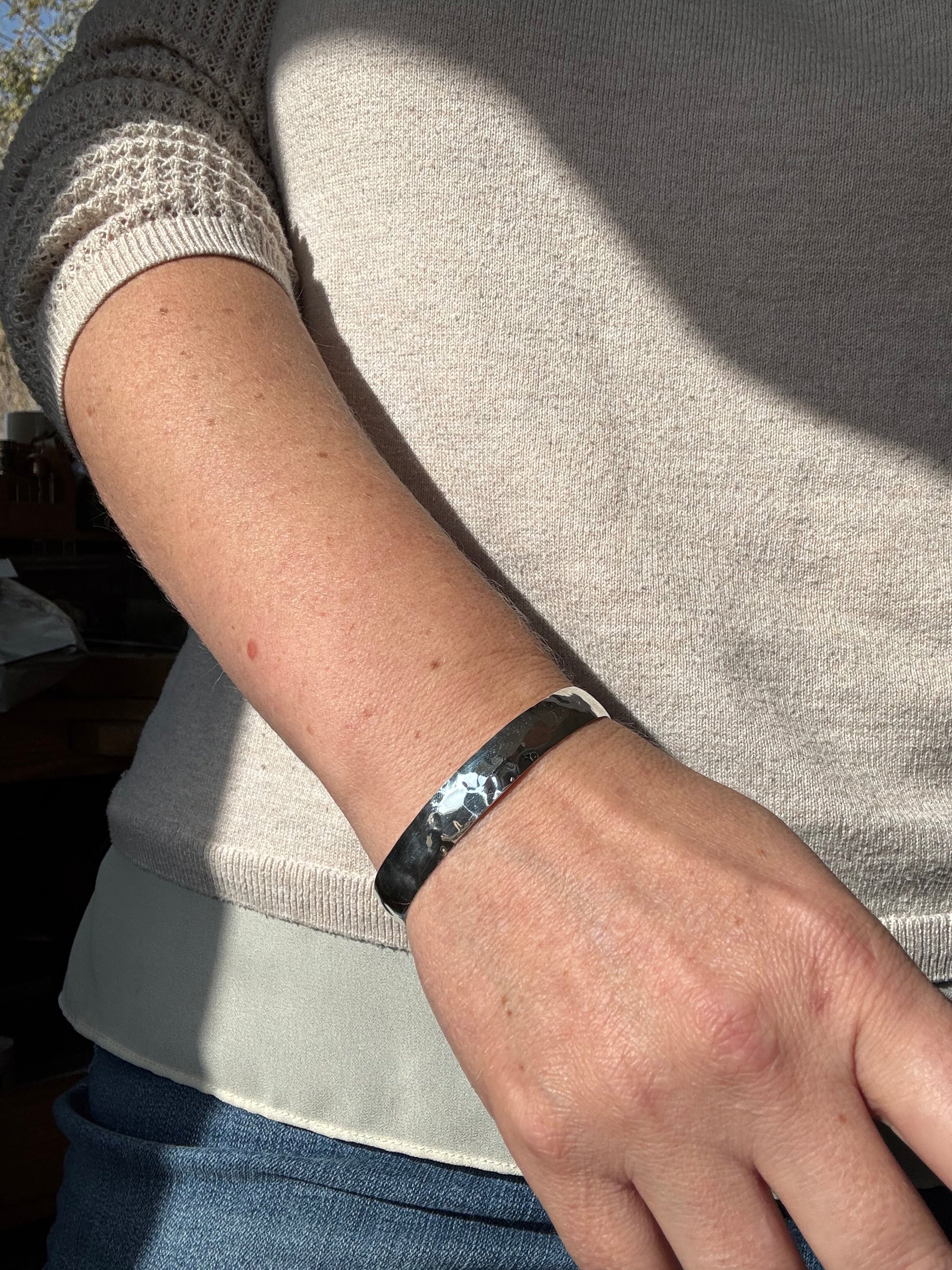 Person wearing a black bracelet on a light-colored sweater