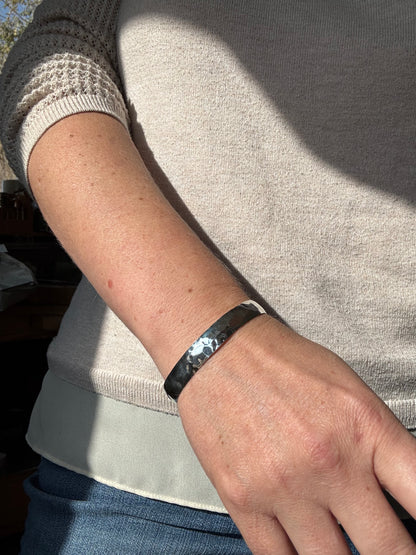 Person wearing a black bracelet on a light-colored sweater