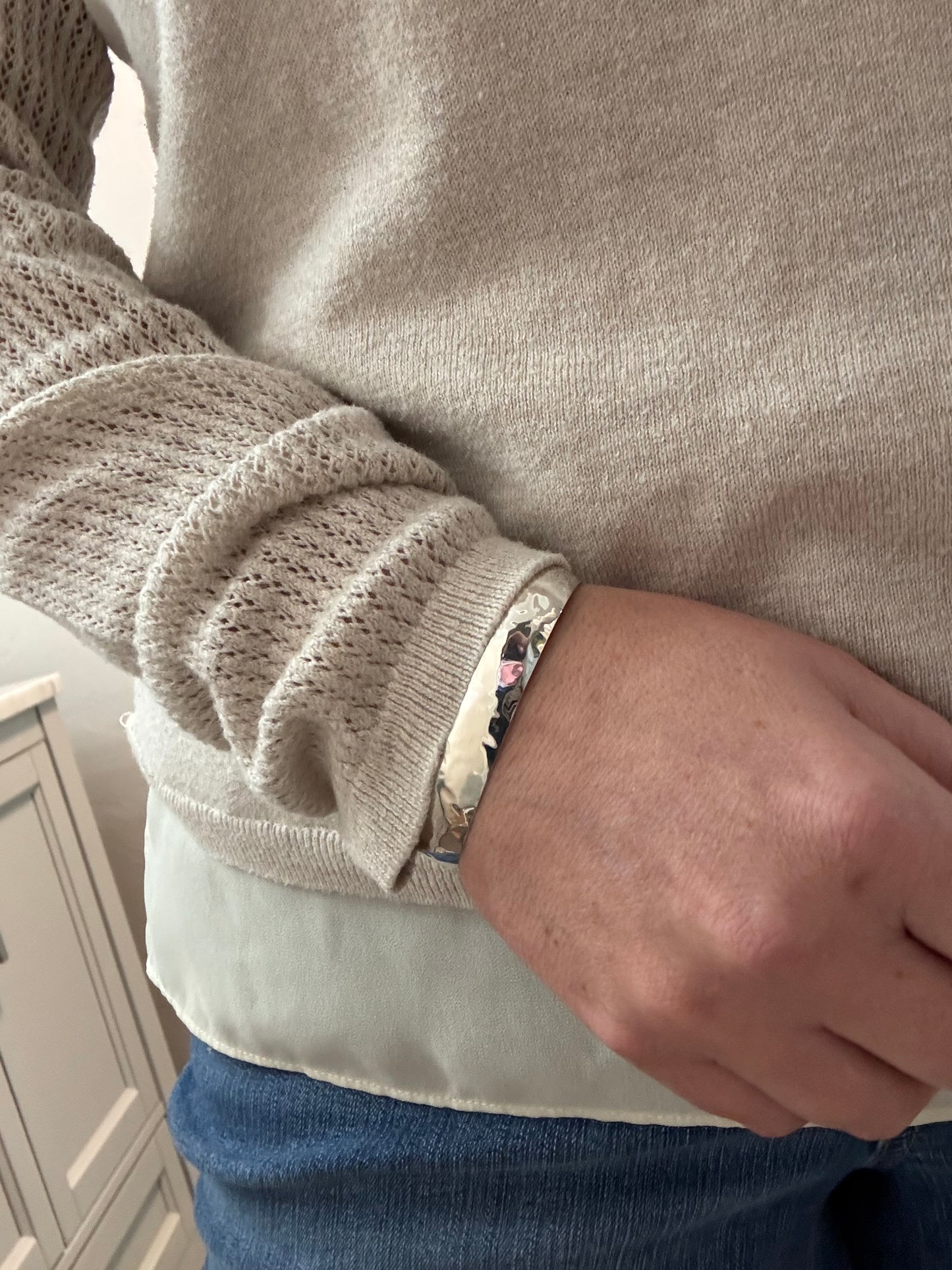 Close-up of a person wearing a patterned bracelet on a neutral background