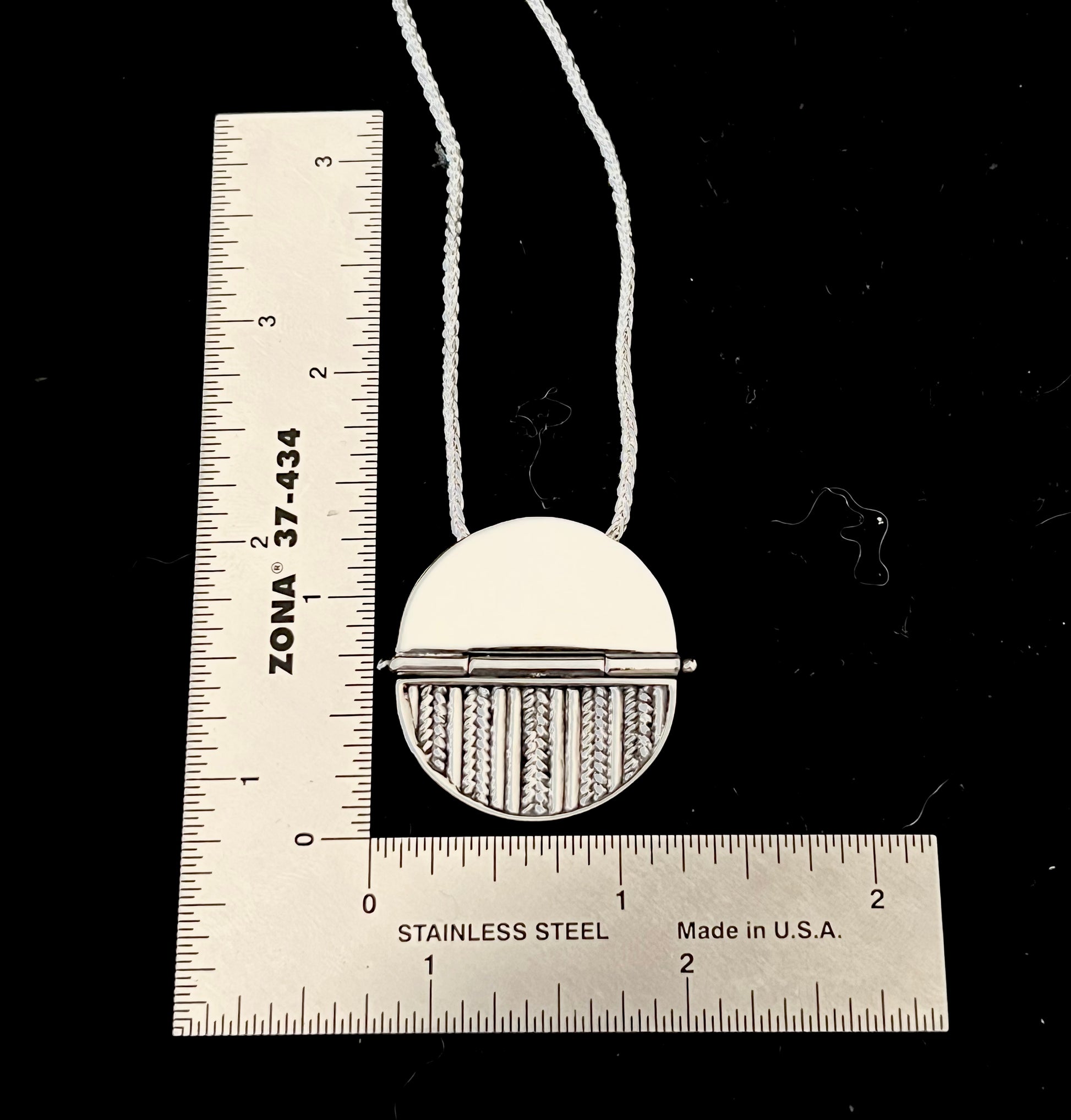 Sterling Silver Hinged Sweater Pendant Necklace – size reference showing sterling silver knit-texture disc pendant approximately 1 inch wide next to ruler, black background