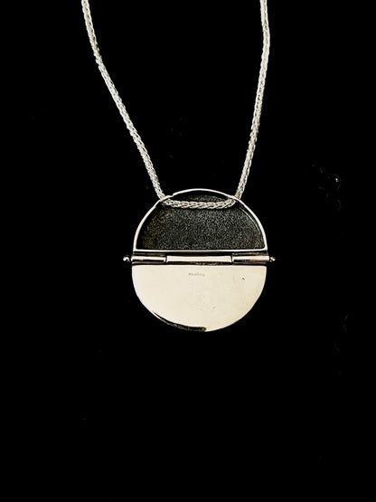 Sterling Silver Hinged Sweater Pendant Necklace – lifestyle shot of handcrafted sterling silver sweater-texture disc pendant necklace worn on neck, black background