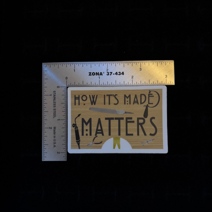 "How It's Made Matters" sticker – size reference showing gold and black rectangular vinyl sticker approximately 2.5 inches wide next to ruler, black background
