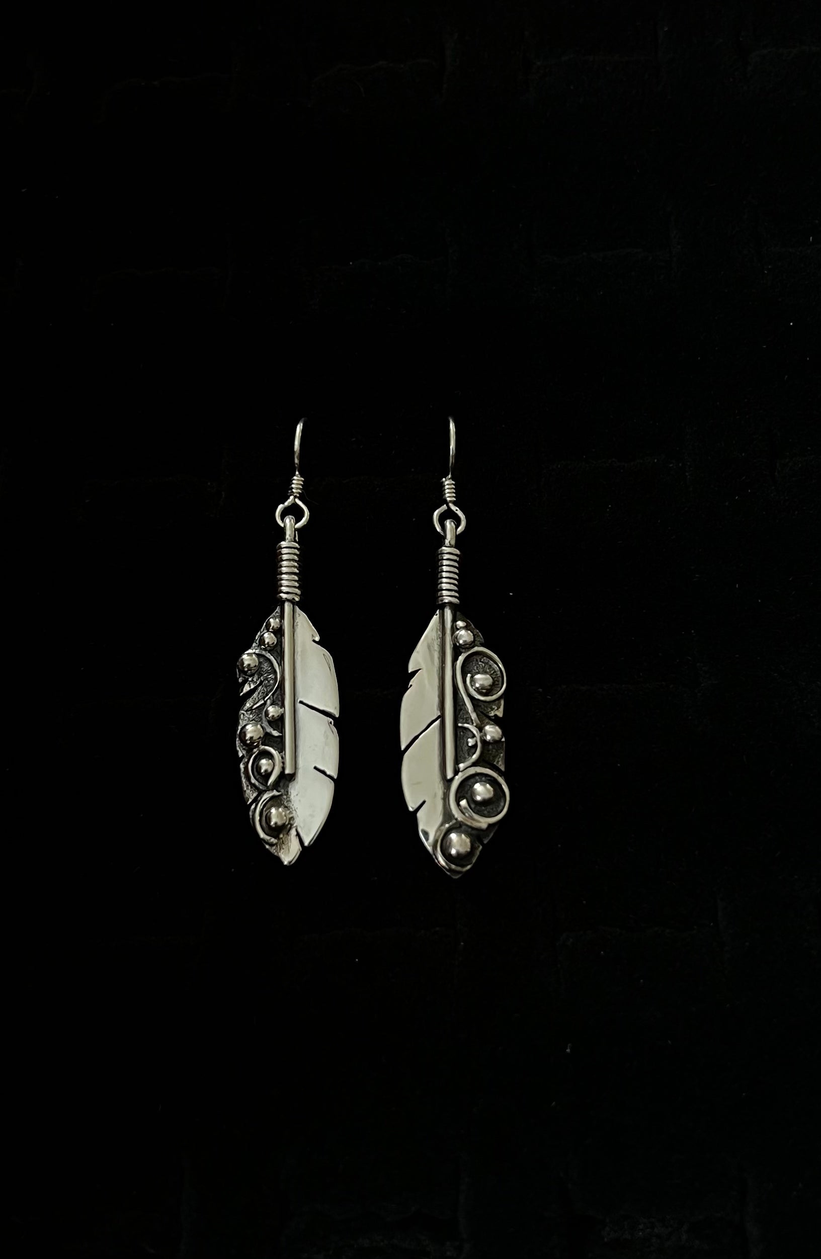 Long Feather Earrings – close-up of sterling silver long oxidized feather drop earrings showing quill and barb texture detail, black background