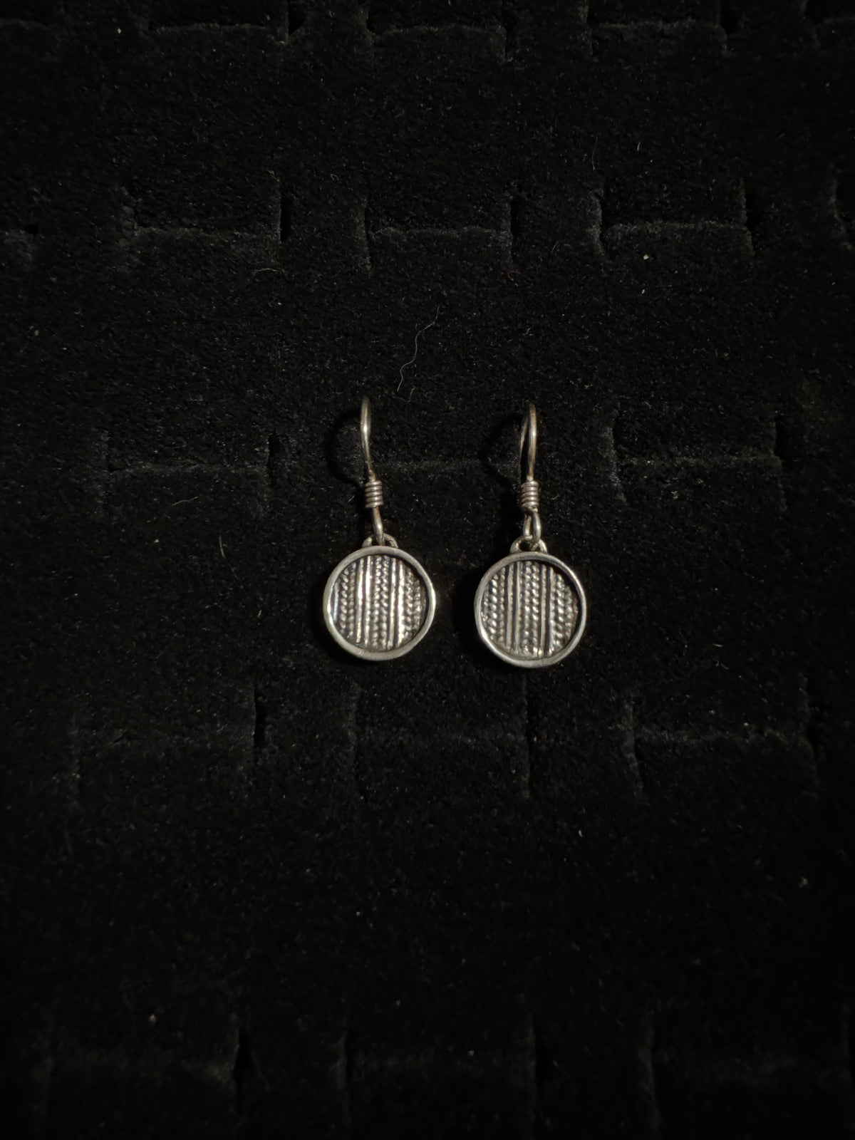 Pair of silver badminton racket earrings on a dark textured background