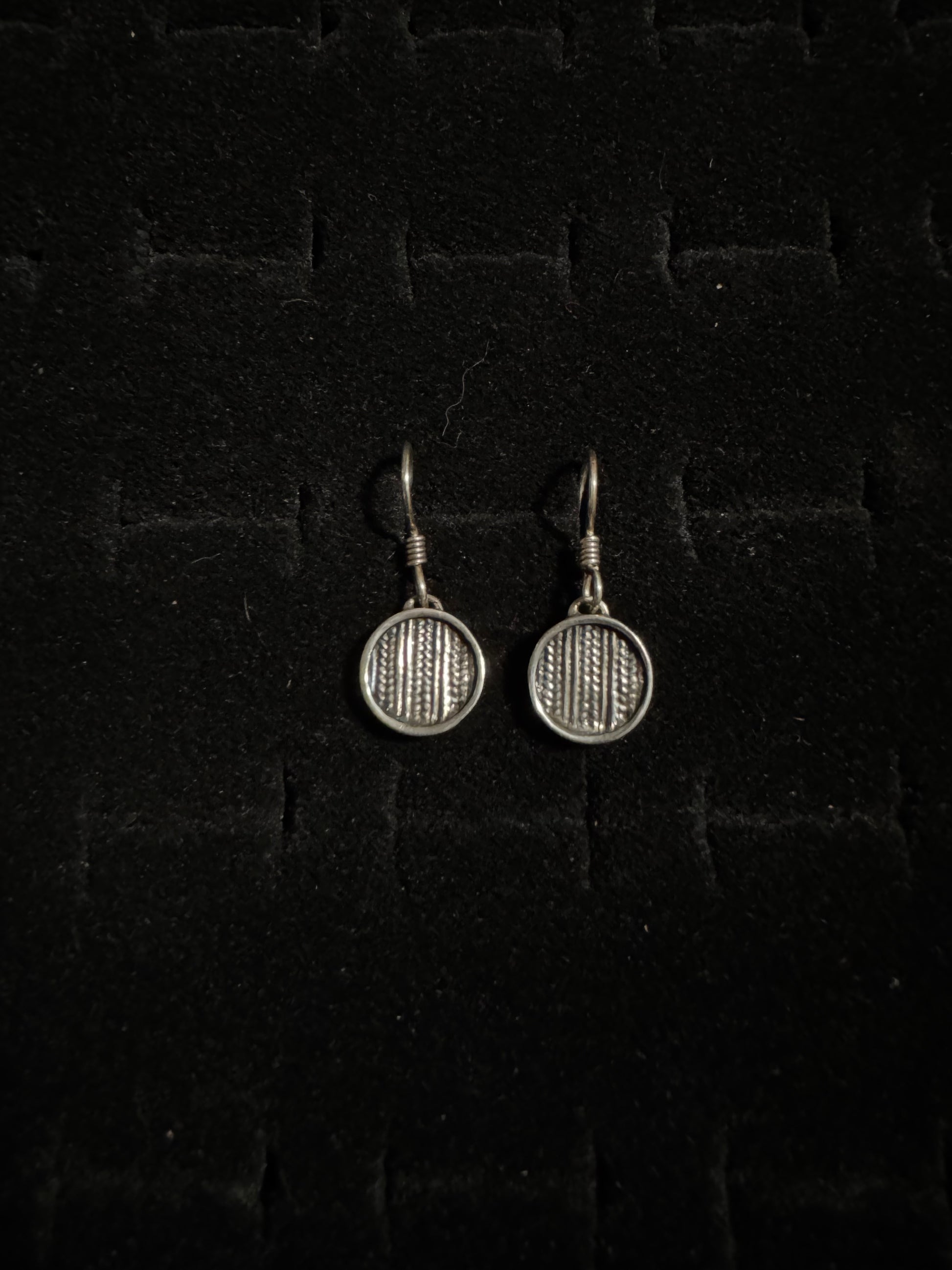 Pair of silver badminton racket earrings on a dark textured background