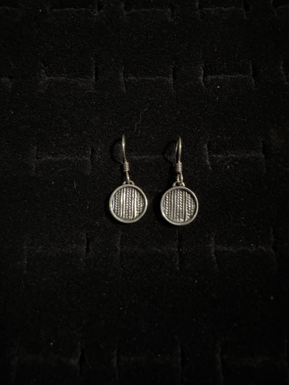 Pair of silver badminton racket earrings on a dark textured background