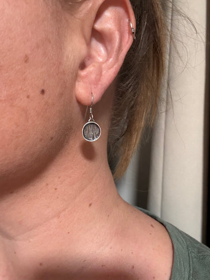 Close-up of an ear with a silver earring worn by a person.