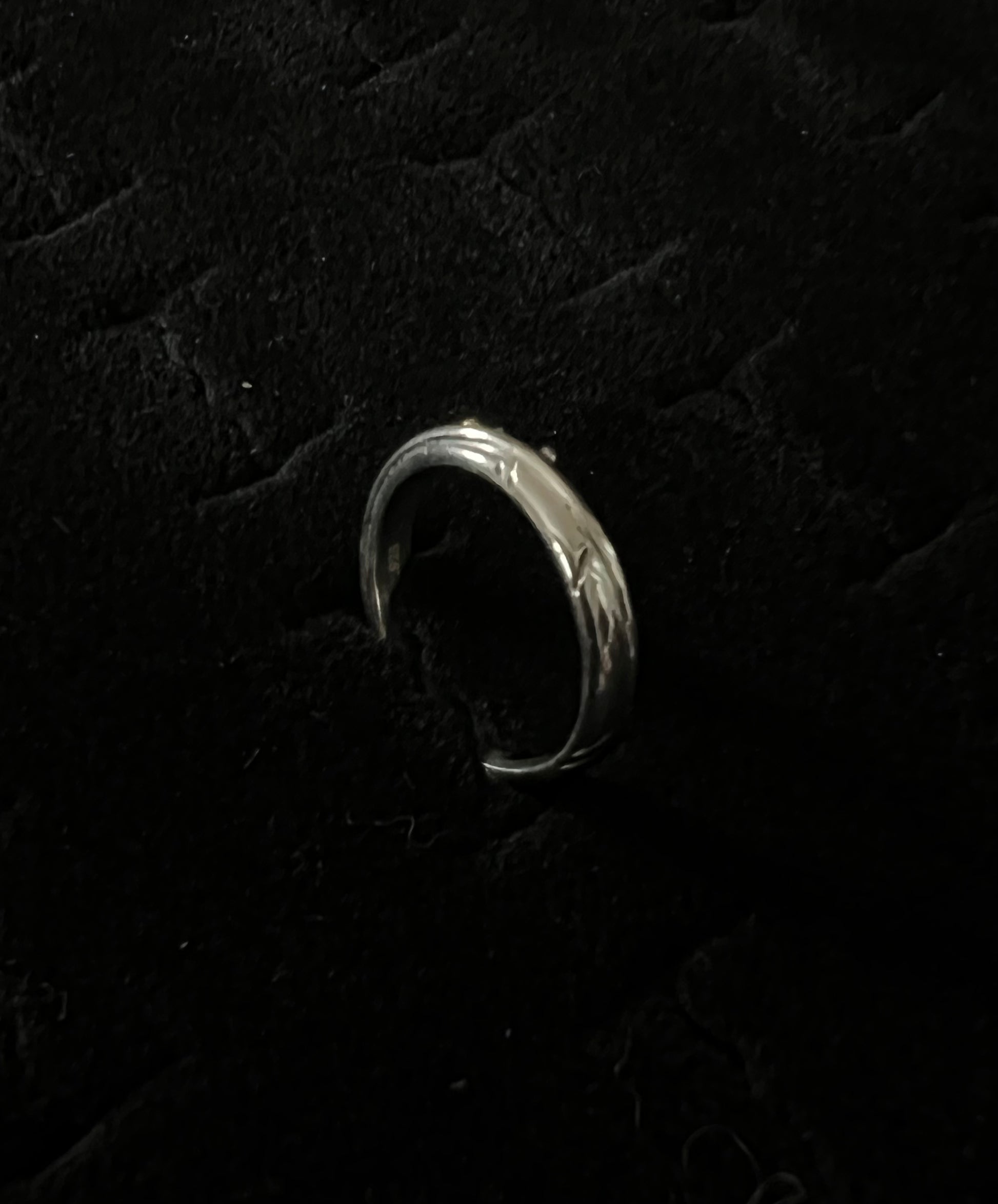 Narrow Feather Ring – overhead view of handcrafted sterling silver narrow feather band ring, black background