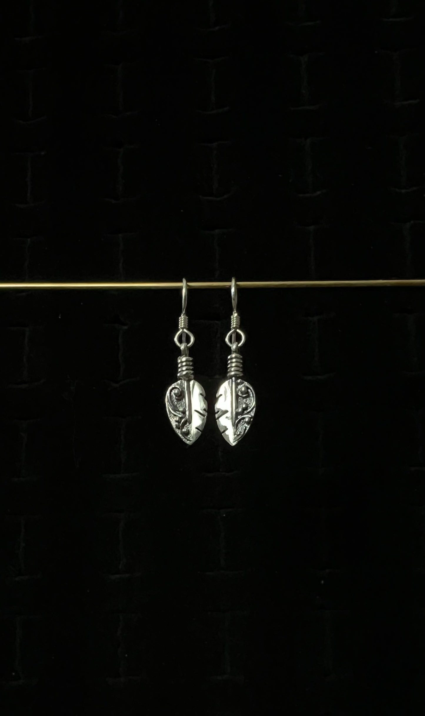 Petite Feather Earrings – pair of handcrafted sterling silver small oxidized feather drop earrings with detailed quill and barb texture on french hooks, black background