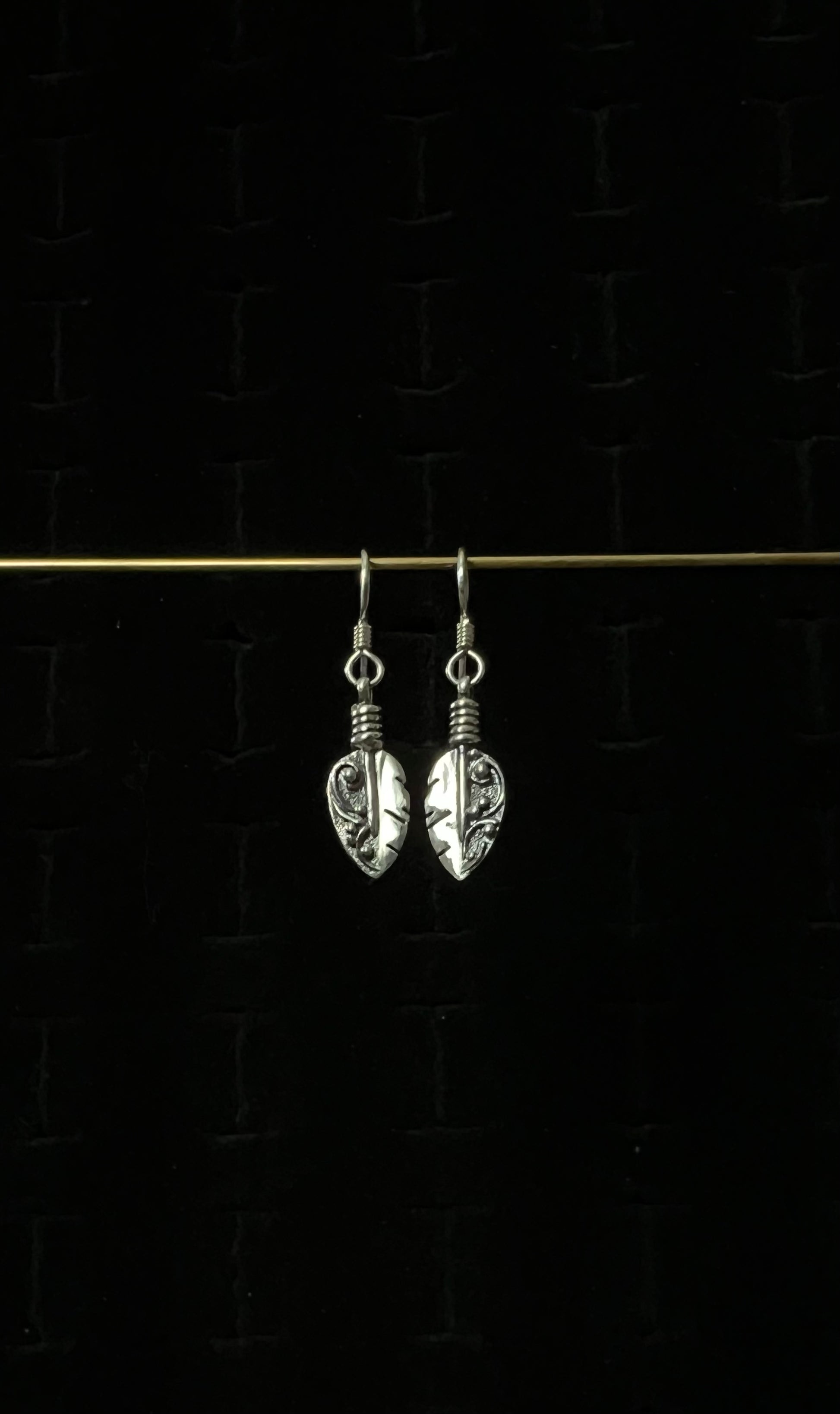Petite Feather Earrings – pair of handcrafted sterling silver small oxidized feather drop earrings with detailed quill and barb texture on french hooks, black background
