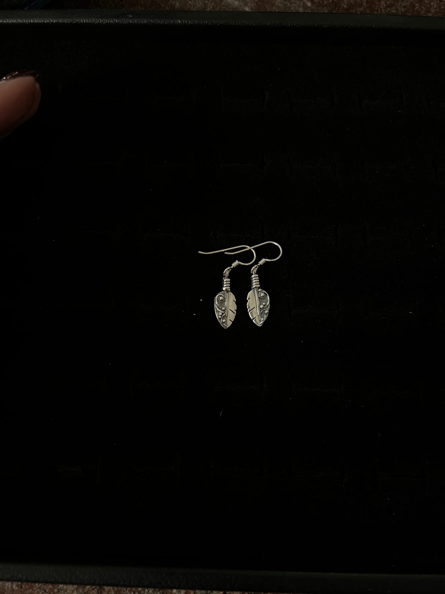 Petite Feather Earrings – front view of handcrafted sterling silver petite oxidized feather drop earrings on french hooks, black background