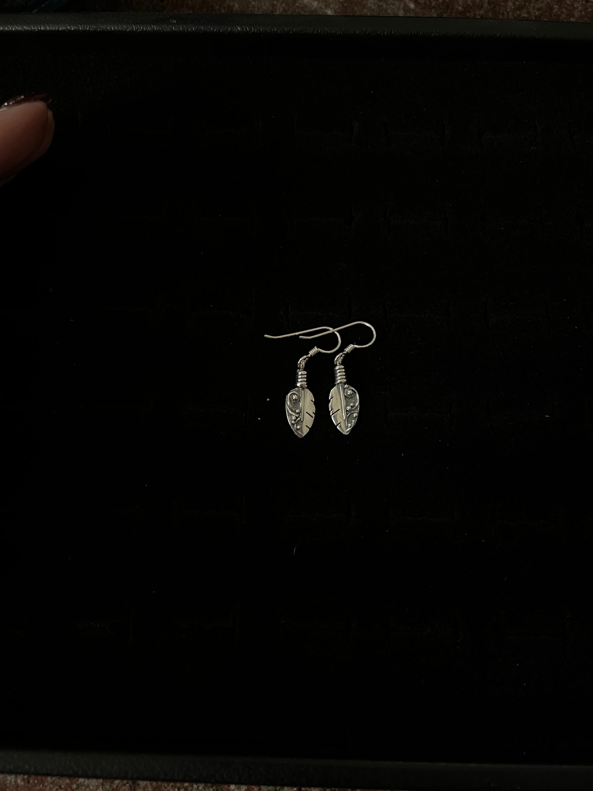 Petite Feather Earrings – front view of handcrafted sterling silver petite oxidized feather drop earrings on french hooks, black background