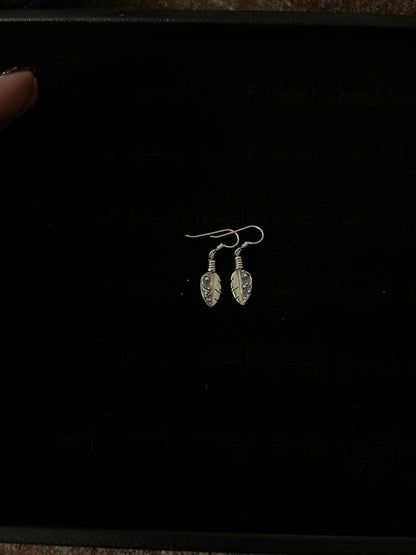 Petite Feather Earrings – front view of handcrafted sterling silver petite oxidized feather drop earrings on french hooks, black background