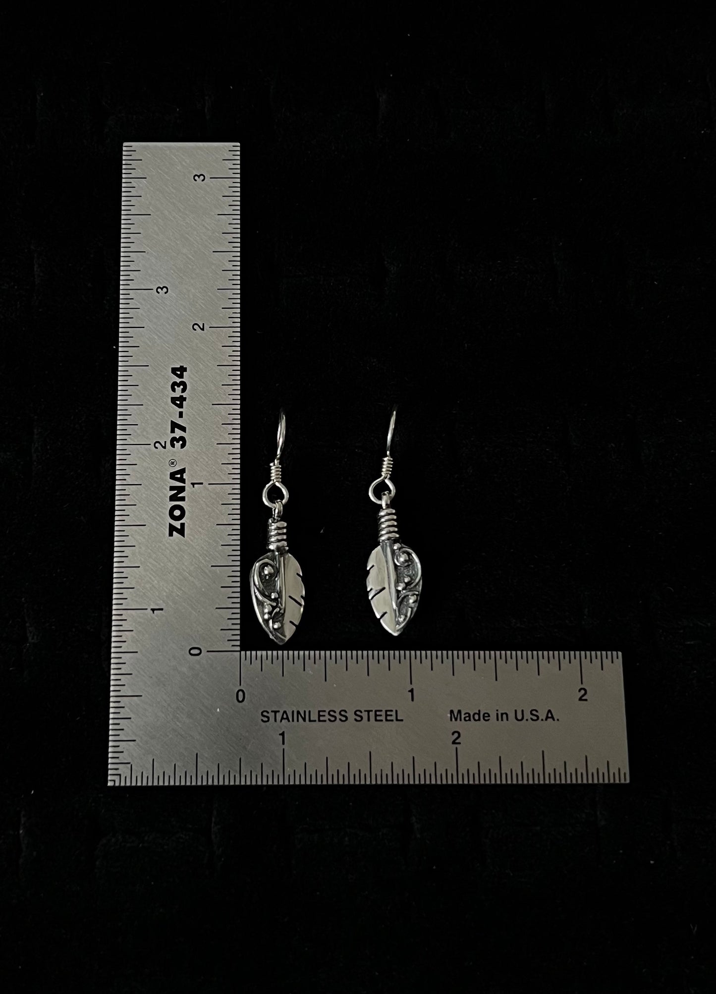 Petite Feather Earrings – overhead view of handcrafted sterling silver petite oxidized feather drop earrings, black background