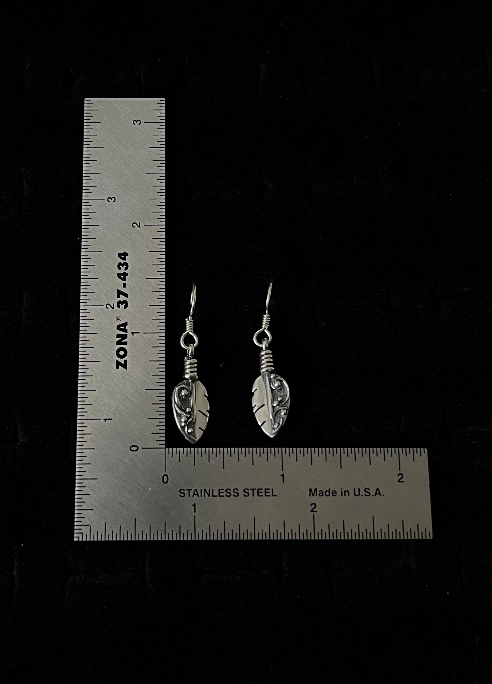 Petite Feather Earrings – overhead view of handcrafted sterling silver petite oxidized feather drop earrings, black background