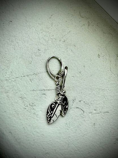Silver leaf-shaped earring on a textured light gray background