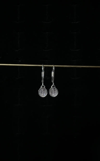 A pair of silver sweater drop lever back earrings displayed against a dark background.
