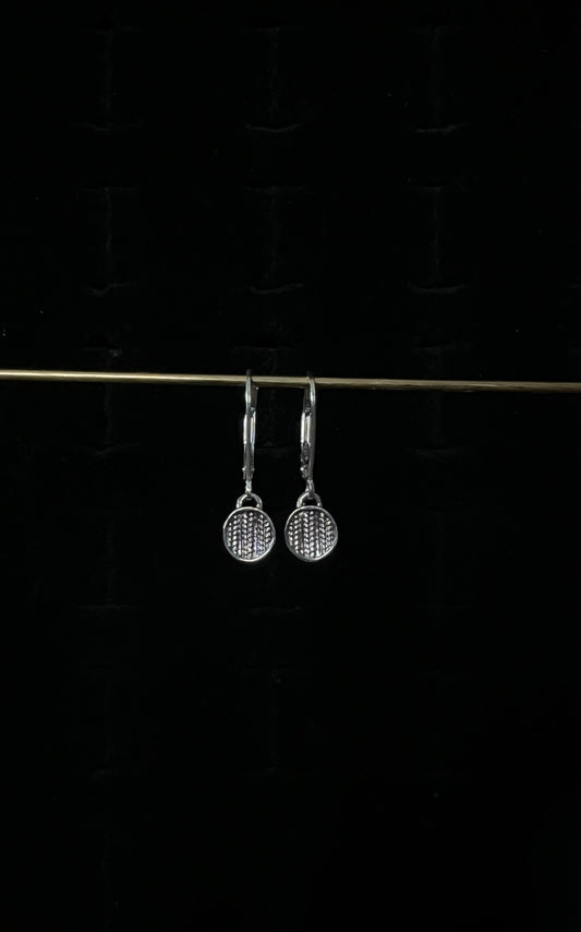 A pair of silver sweater drop lever back earrings displayed against a dark background.