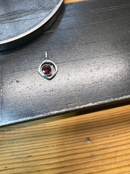 Square-Ring Pendant with Faceted Garnet – handcrafted sterling silver square-shaped ring pendant with bezel-set faceted red garnet stone on box chain, black background