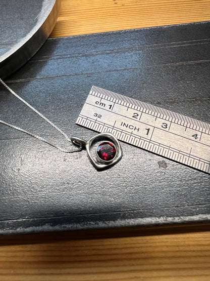 Square-Ring Pendant with Faceted Garnet – size reference showing sterling silver square-ring pendant with faceted garnet approximately 1 inch wide next to ruler, black background