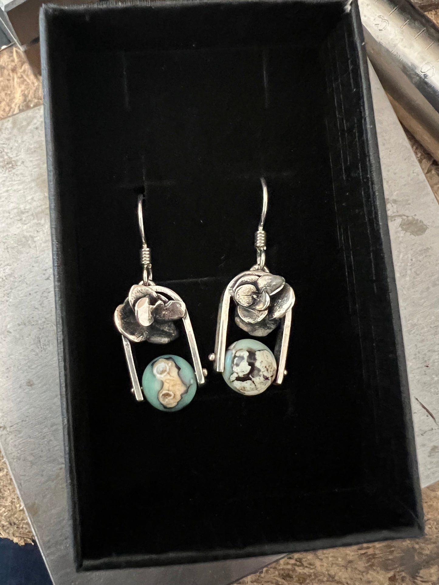 A pair of sterling silver earrings with aqua terra agate beads, displayed in a black box.