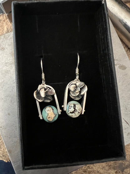 A pair of sterling silver earrings with aqua terra agate beads, displayed in a black box.