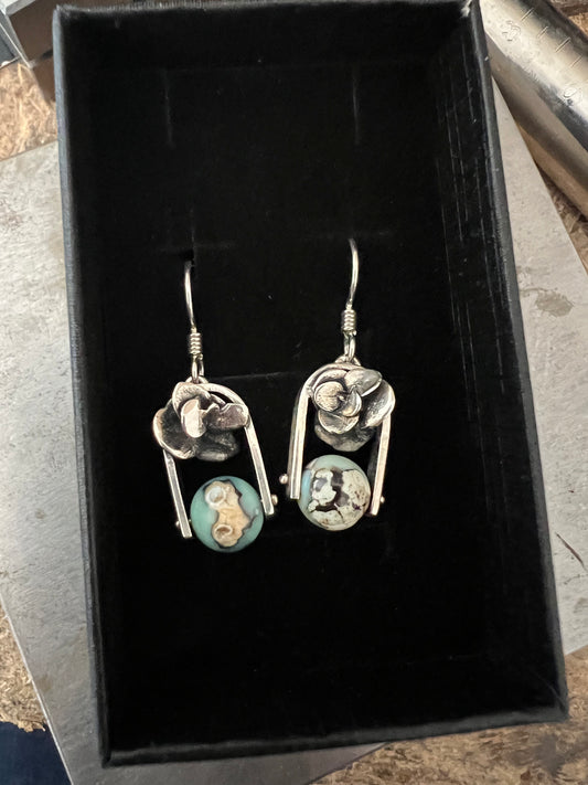 A pair of sterling silver earrings with aqua terra agate beads, displayed in a black box.