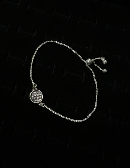 An adjustable sterling silver bracelet with a sweater pattern design on a dark background.