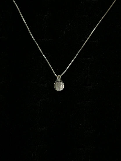 A silver necklace with a pendant designed to resemble a sweater, displayed against a black background.