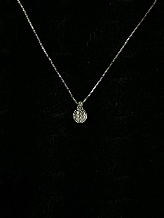 A silver necklace with a pendant designed to resemble a sweater, displayed against a black background.