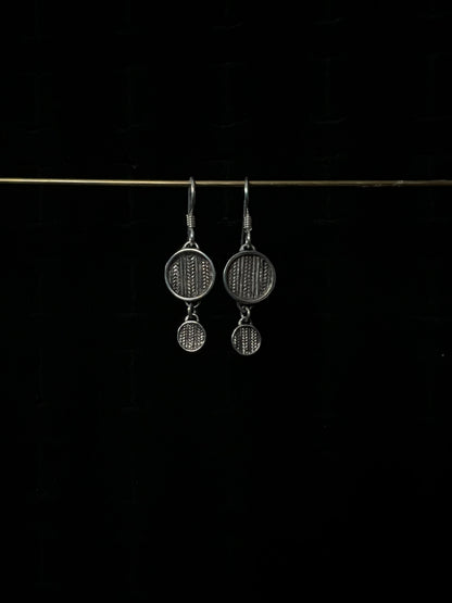 A pair of silver tiered sweater drop earrings displayed against a dark background.