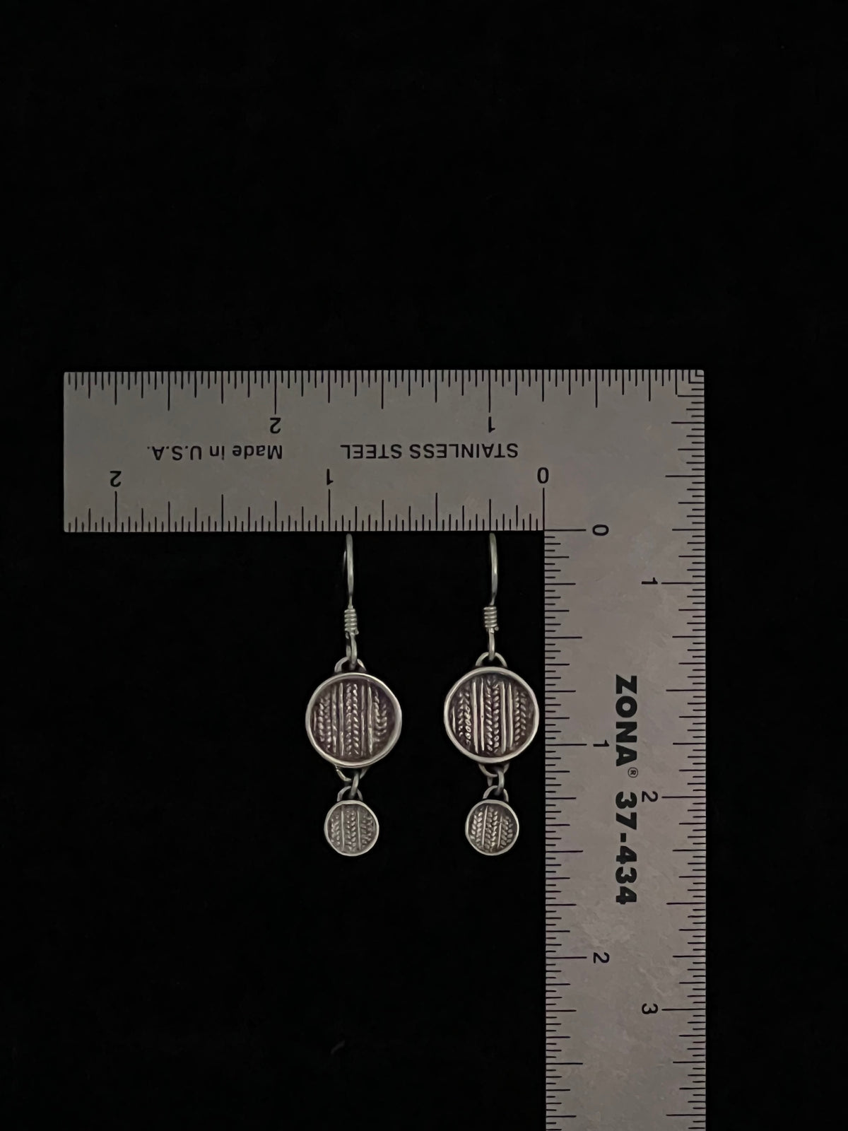 Tiered Sweater Drop Earrings – size reference showing sterling silver two-tier knit-texture disc drop earrings approximately 1.5 inches long next to ruler, black background