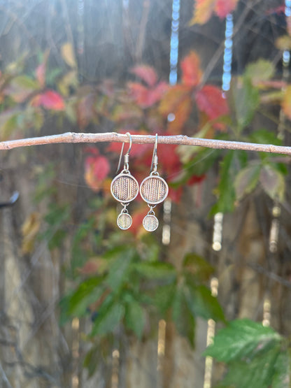 Tiered Sweater Drop Earrings – lifestyle shot of handcrafted sterling silver tiered sweater-texture disc earrings resting on dark knit sweater near fireplace