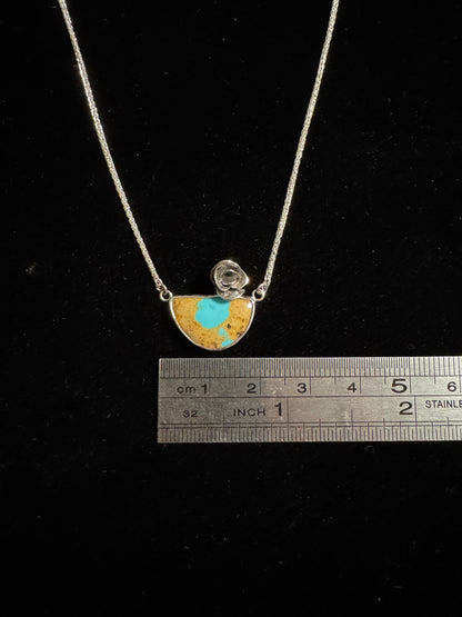 Necklace with a pendant and a ruler for scale on a black background