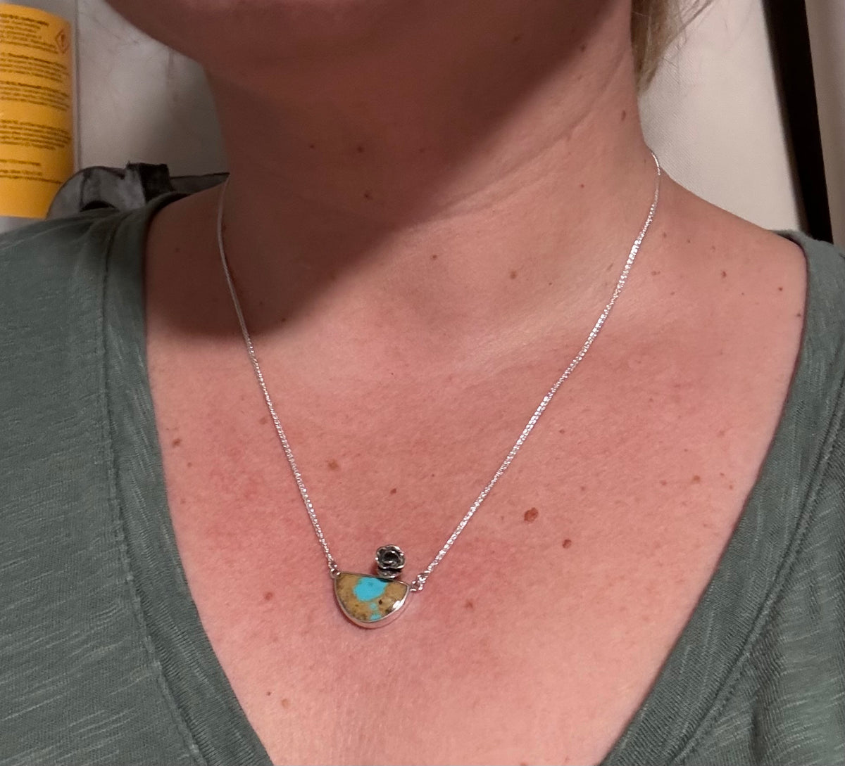 Necklace with a pendant worn by a person, close-up view.