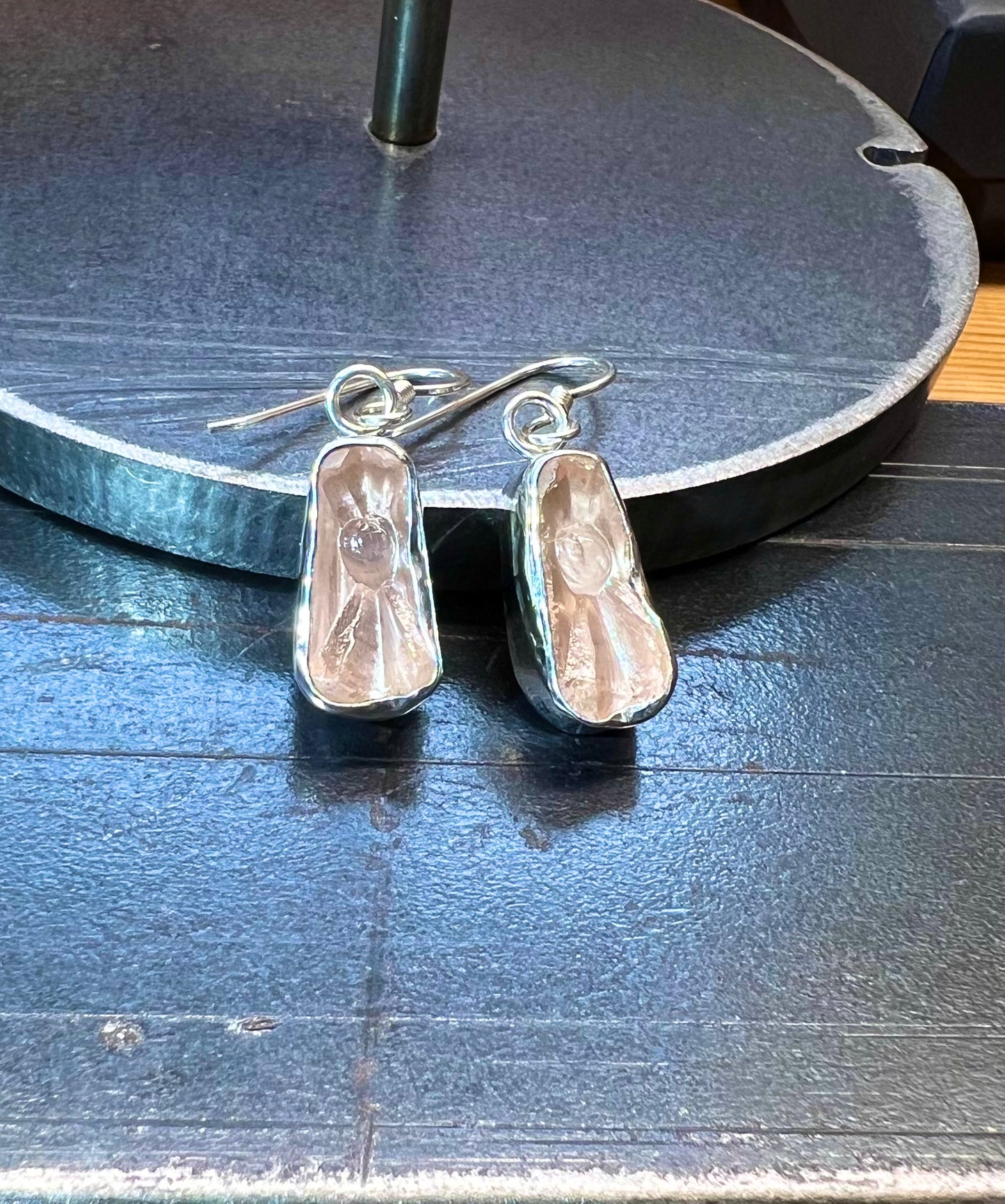 A pair of vintage glass earrings with bezel settings in silver, displayed on a dark surface.